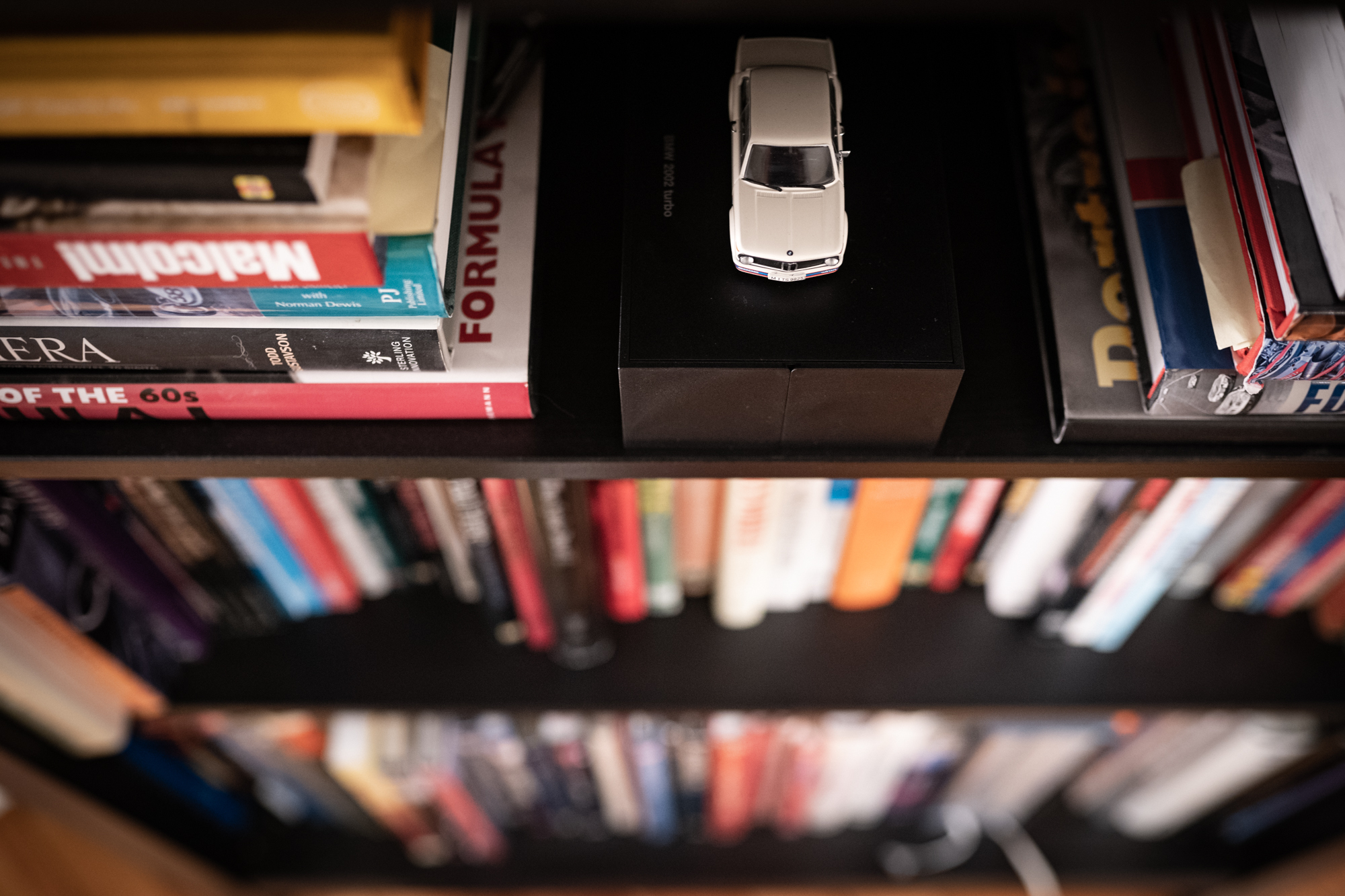 white bmw 2002 miniature on bookcase shelf