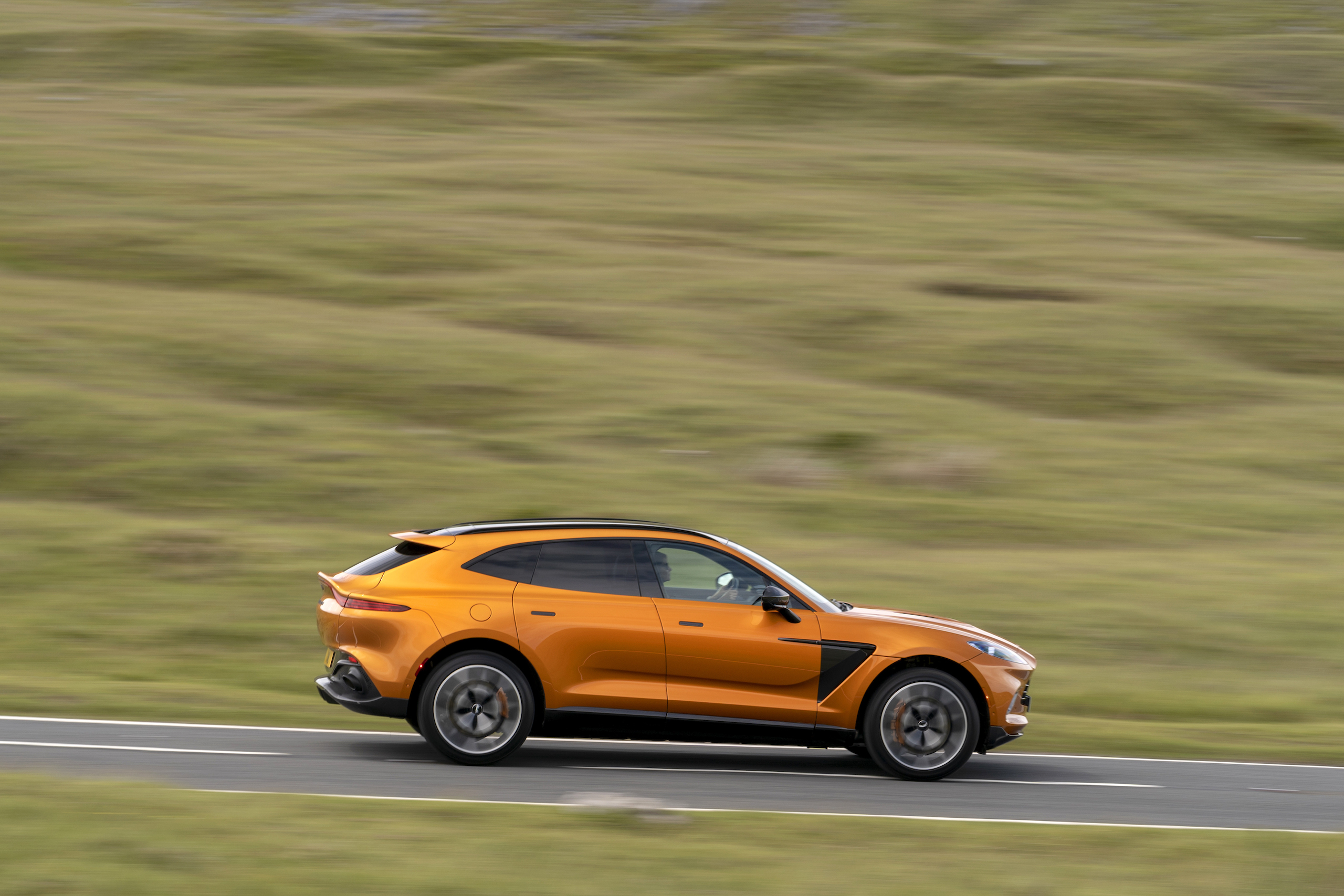 aston martin new dbx suv golden saffron profile road action