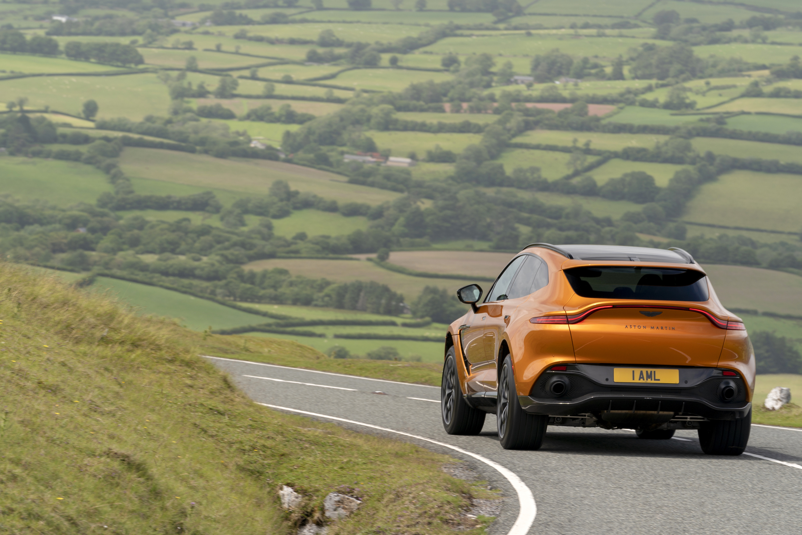 aston martin new dbx suv golden saffron rear country road action