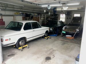 packed garage of bmw lotus vintage cars