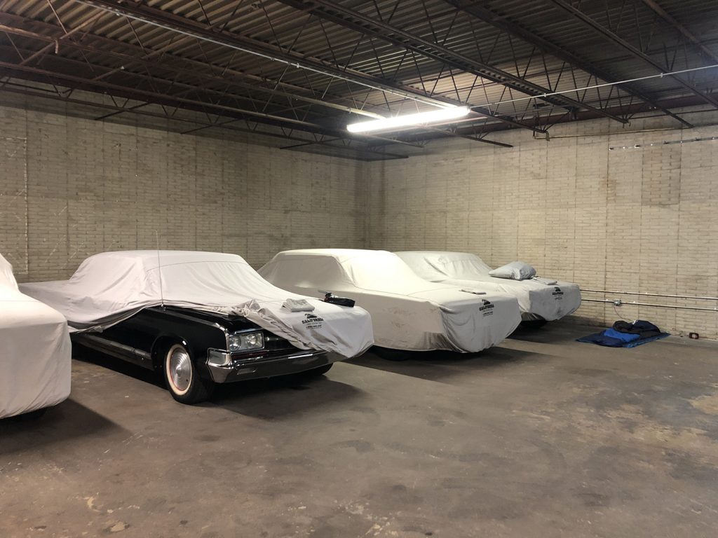 Sleeping bag in garage of covered classic cars