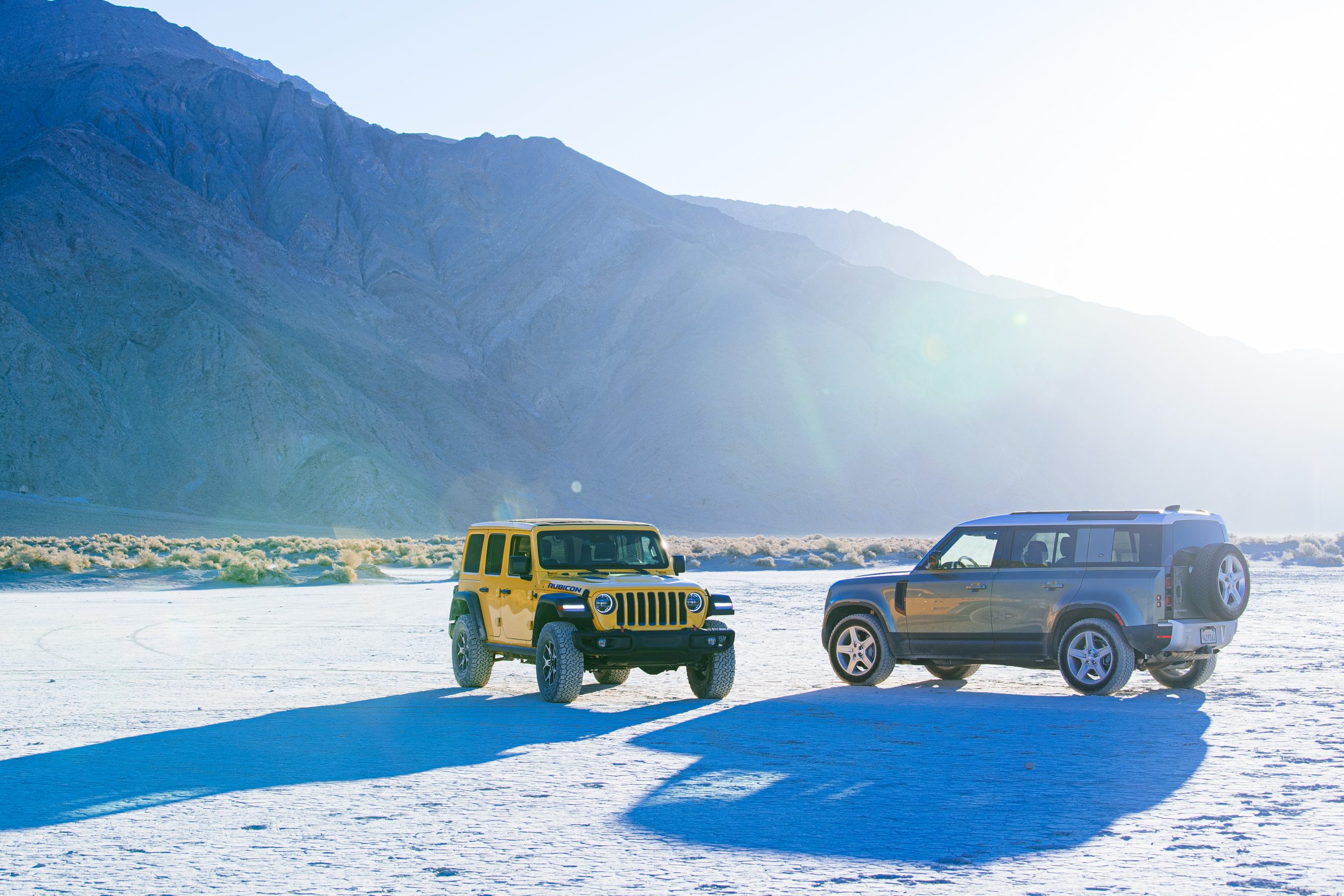 jeep wrangler rubicon and land rover defender on deserted flat