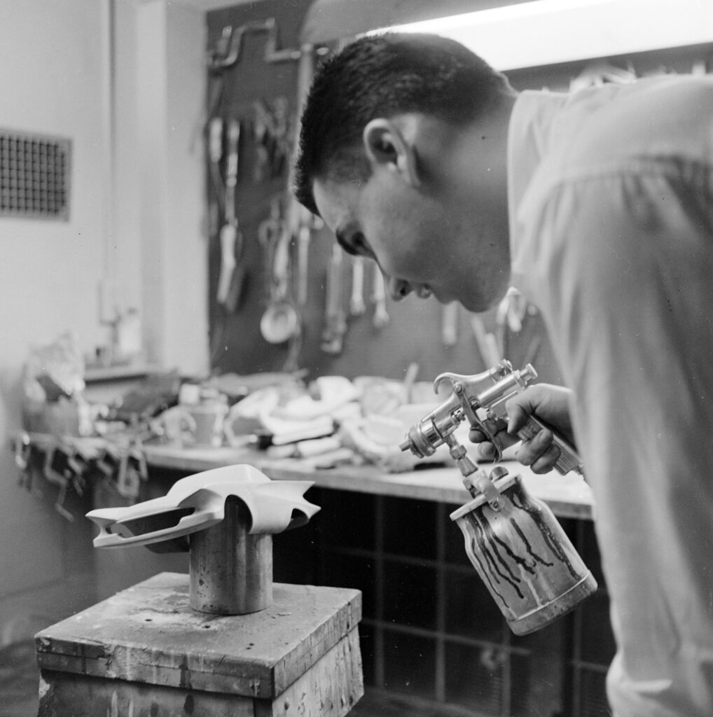 Professional model car maker spraying a scale model of a prototype car for American car