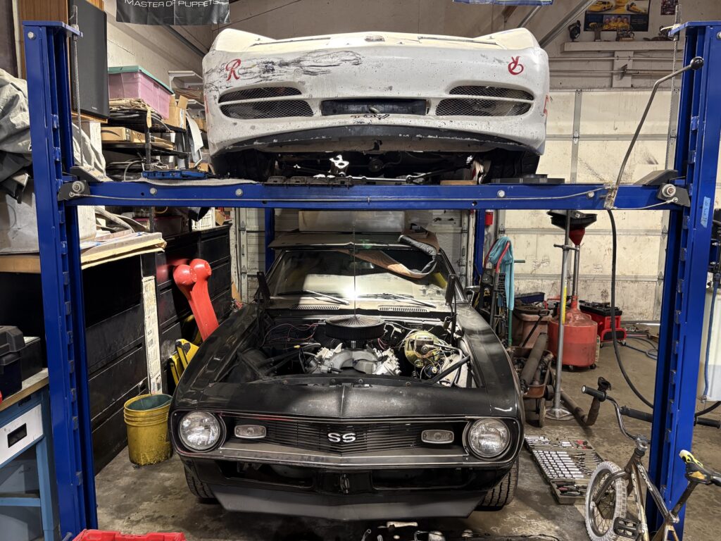 A view of multiple cars in the shop with ongoing projects.